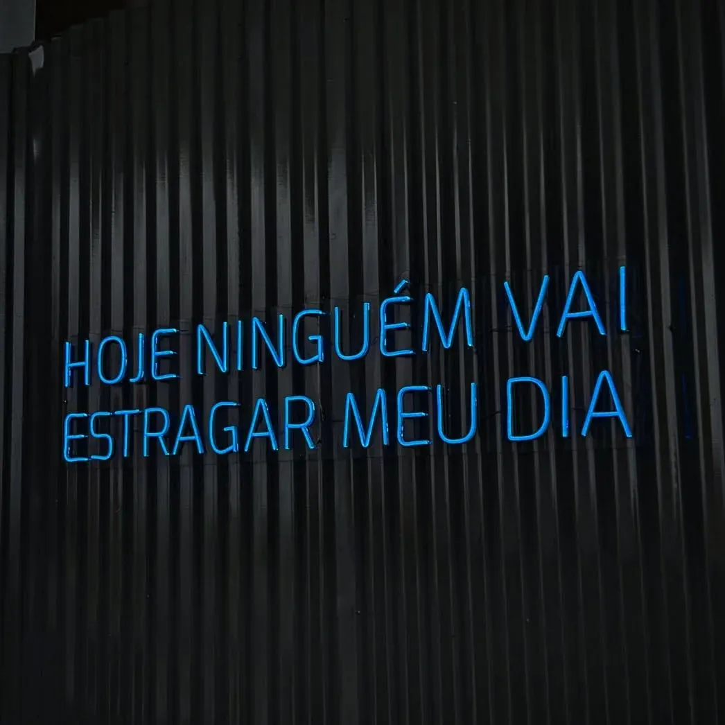 Frase motivacional 'Good Times Tan Lines' em Neon LED na parede de clube de praia
