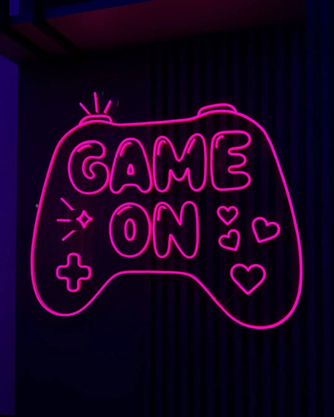 Letreiro em Neon LED rosa 'Game On' instalado em quarto gamer