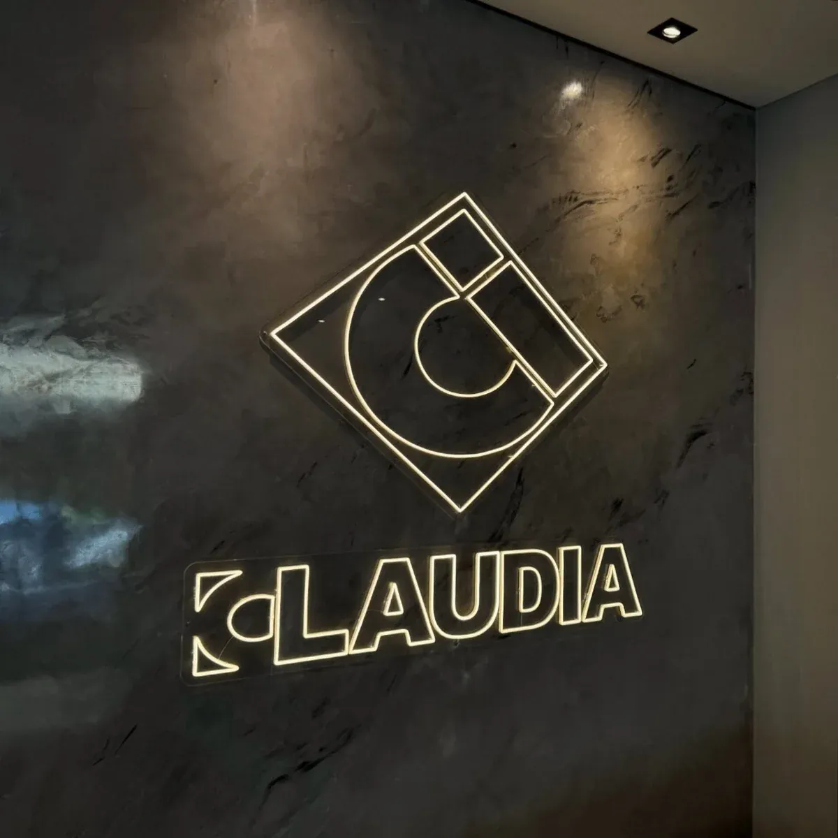 Logotipo da Construtora Claudia em Neon LED branco quente na parede de sala comercial